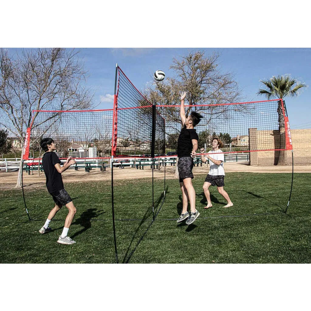 Three people using Powernet Volleyball Four Square Net in a field to play volleyball