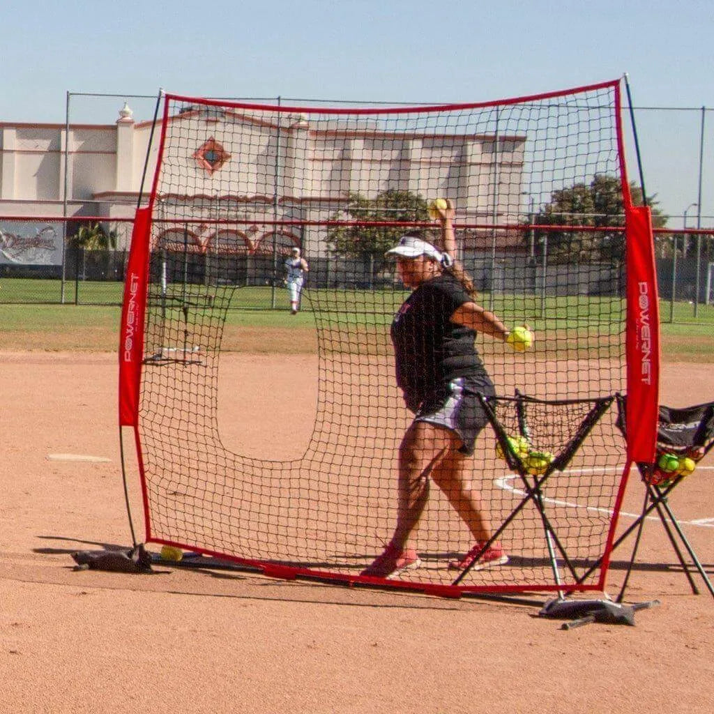 A girl behind Powernet 7x7 FT Pitch-Thru Protection Screen for Softball 49 SQFT Barrier 1090 throwing baseball