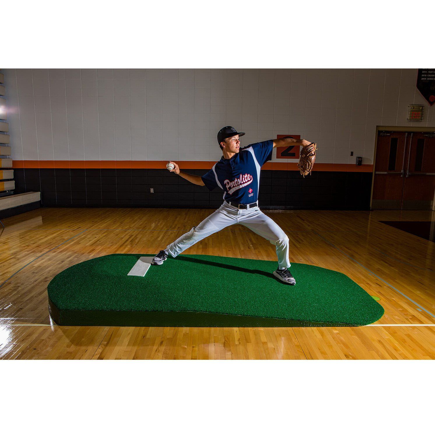 Portolite 10" One-Piece Portable Baseball Practice Pitching Mound 1150 - on the floor indoors with man throwing a ball