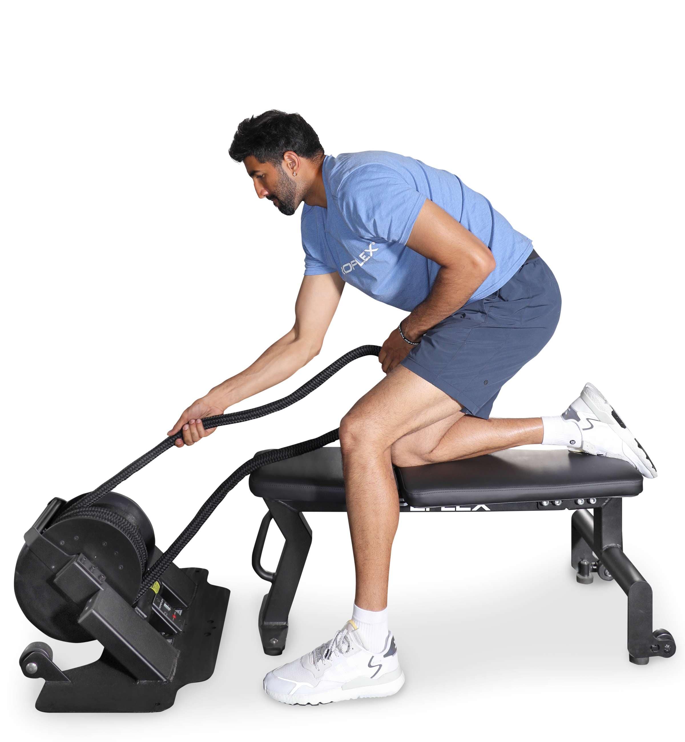 Ropeflex RXB2 Flat Bench - A man in a blue shirt is half-kneeling on a flat bench while pulling a rope in a gym machine