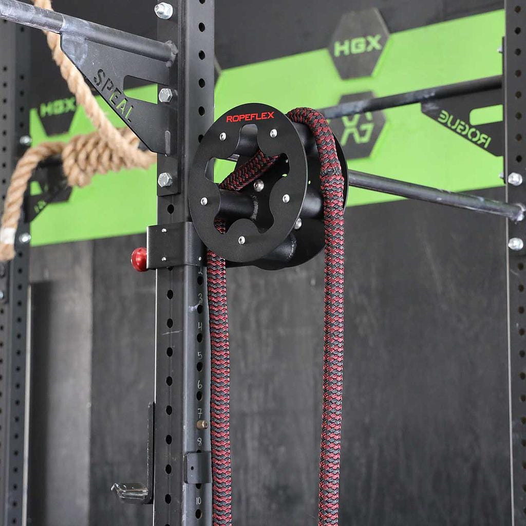 RopeFlex RX505 Hydra Friction Rope Training Drum - A focused photo of a rope-pulling gym equipment hanged on a squat rack