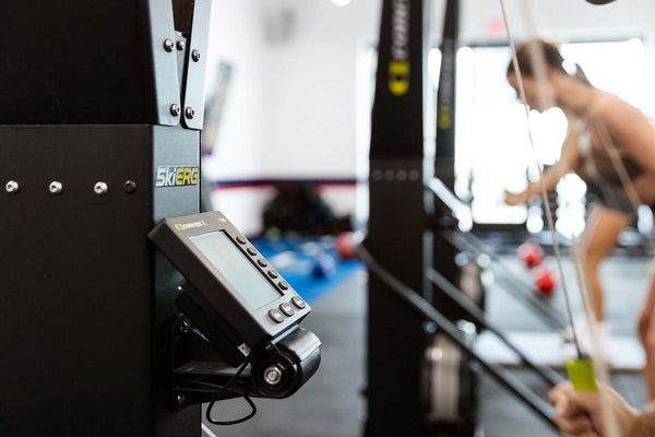 Skierg Concept 2 monitor and equipment in a fitness studio with fitness enthusiast in the background.