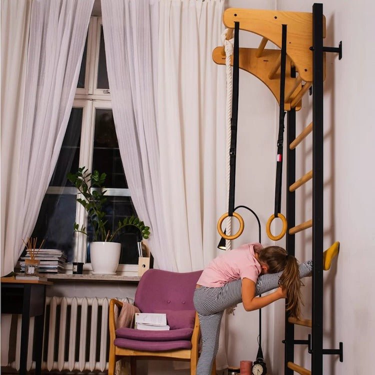 BenchK Series 2 211 + A076 Swedish Ladder for Kids With Gymnastic Accessories - A girl with one leg on wall bar stretching 