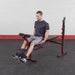 Best Fitness BFOB10 Olympic Bench With Leg Developer - man sitting on bench with weights on foot support cushioned