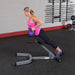 Body-Solid 45° Back Hyperextension GHYP345 - Woman in pink top using GHYP345 while holding 2 purple kettlebells