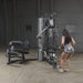 Body-Solid Bi-Angular Multi-Stack Gym G10B - Woman doing arm exercise while bending in front of multi stack gym