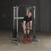 Body-Solid Compact Functional Training Center GDCC210 Man standing on a training chair while holding a bar