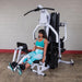 Body-Solid EXM3000LPS Multi-Stack Home Gym - Woman sitting on bench while doing leg extension 