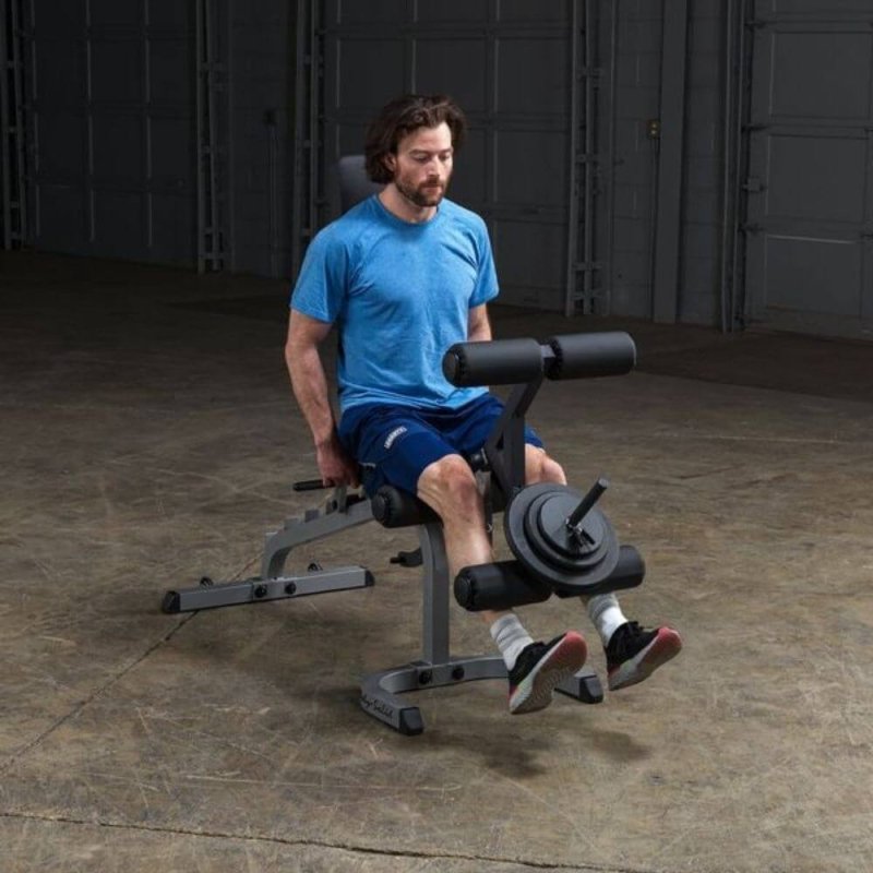 Body-Solid Flat Incline Decline Bench GFID31 - A man working out on leg raise using foot support with weight plates on top