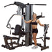 Body-Solid Fusion 500 Modular Single Stack Gym F500 woman standing in front of the actual product