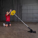 Body-Solid Home Plate T-Bar Row Landmine TBR50 - Man working out knee down holding the tip of the rod with color yellow plate