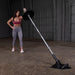 Body-Solid Home Plate T-Bar Row Landmine TBR50 - woman holding the rod in one hand with one plate in black on it