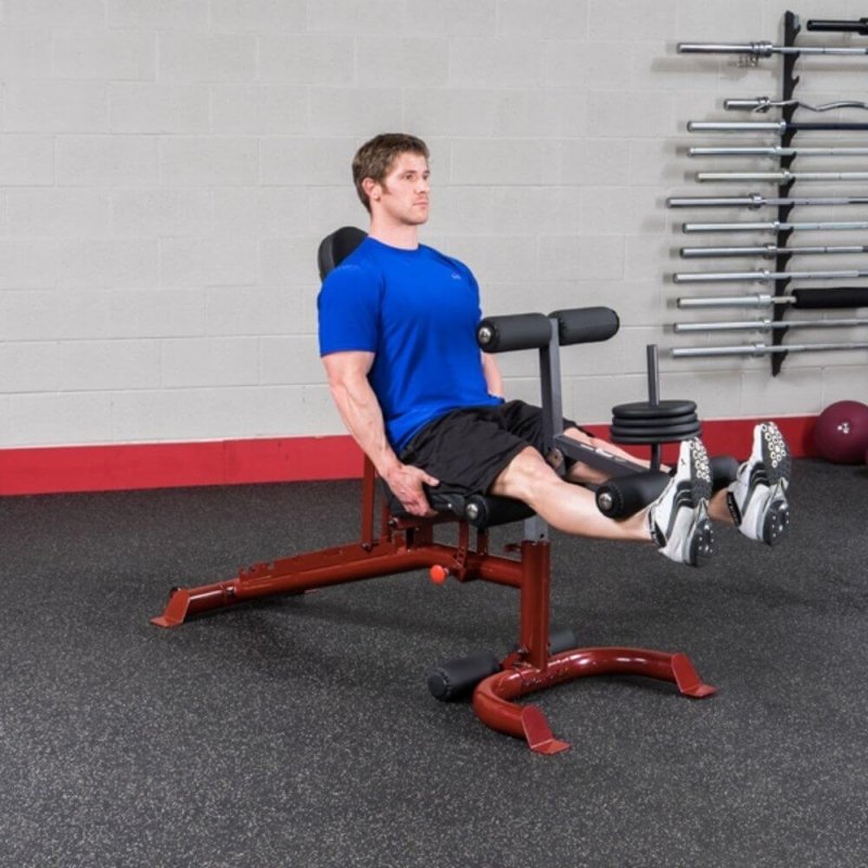 Body-Solid Leg Developer Attachment GLDA3 - Man sitting on the bench doing leg rais while using leg support