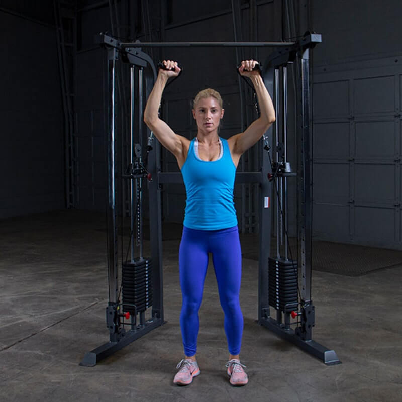 Body-Solid Powerline PFT100 Functional Trainer - woman standing next to metal bar