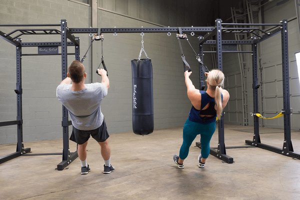 Body Solid Pro Club Line Power Rack, Half Rack Connecting Bar - man and woman doing the same exercise routine  