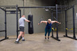 Body Solid Pro Club Line Power Rack, Half Rack Connecting Bar - man using punching bag