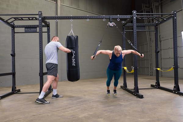 Body Solid Pro Club Line Power Rack, Half Rack Connecting Bar - man using punching bag