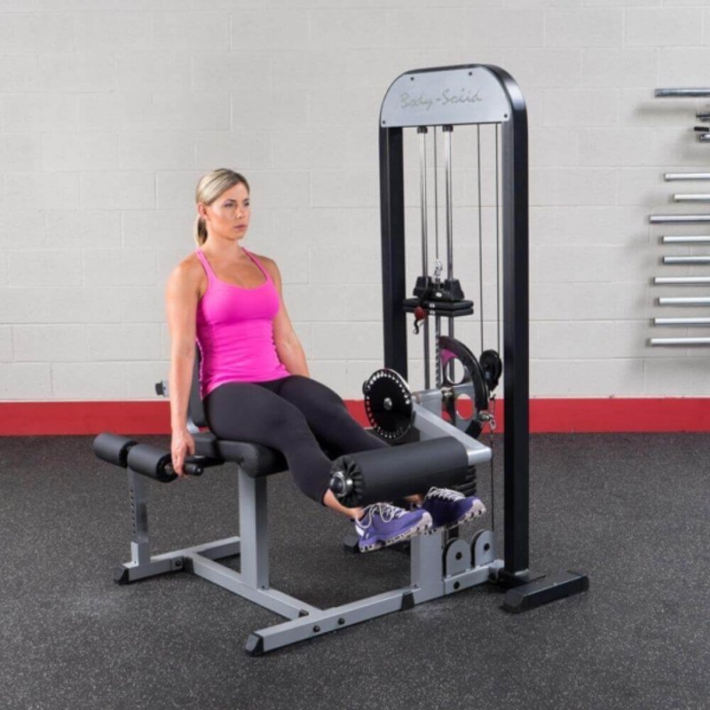 Body-Solid Pro Select Leg Extension Leg Curl Station GCEC-STK - Woman holding handles and lifting leg using the cushioned rollers