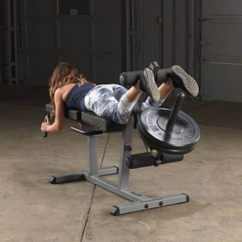 Body-Solid Seated Leg Extension & Supine Curl GLCE365 - woman on training laying down in leg curl exercise