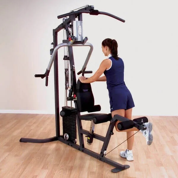 Body-Solid Selectorized Single Stack Home Gym G3S - Woman standing beside G3S pulling weights with her left foot