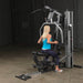 Body-Solid Single Stack Gym G5S - Female model in blue tank top sitting while doing upper body workout