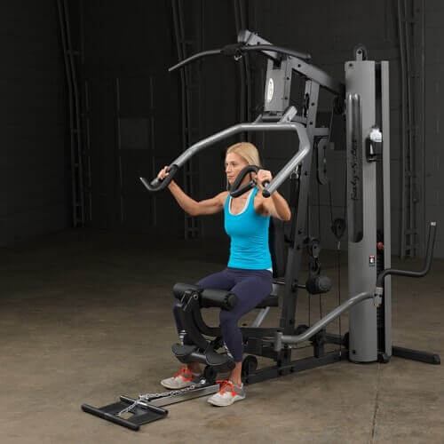 Body-Solid Single Stack Gym G5S - Female model in blue tank top sitting on G1S doing lateral arm workout