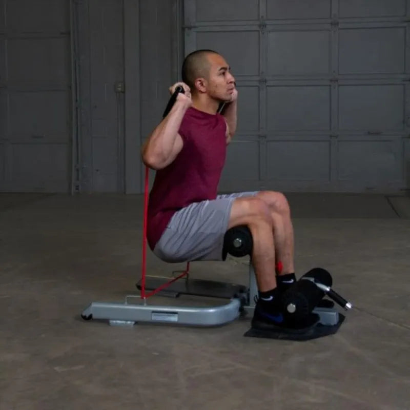 Body-Solid Sissy Squat GSS50 - Man doing squats while holding red gym strings