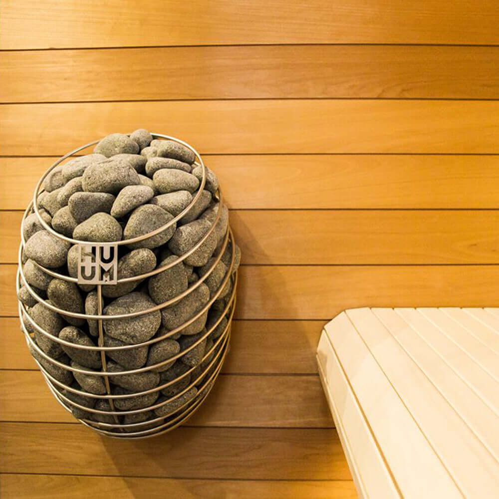 HUUM DROP Series 6.0kW Sauna Heater Package - A basket of sauna rocks attached to a wooden wall