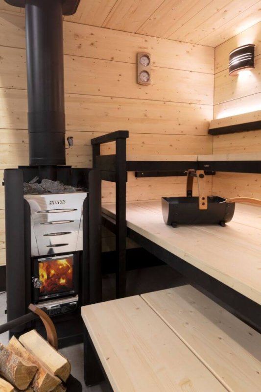 Harvia PRO 20 Series 24kW Wood Stove Sauna Heater - next to wooden benches and firewoods