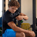 Hyperice Hypervolt 3 Pro - Man sitting down using Hypervolt on his right arm