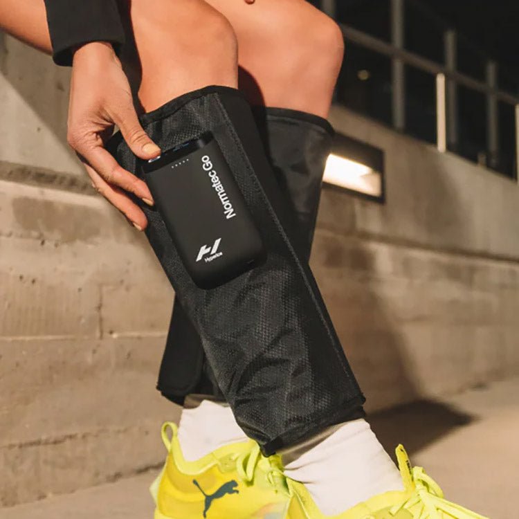 Hyperice Normatec Go - A person wearing yellow shoes wearing the device on both legs