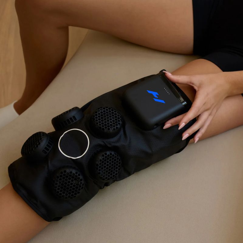 Hyperice X 2 Knee - Close up image of knee compression system worn by a person sitting on a beige sofa