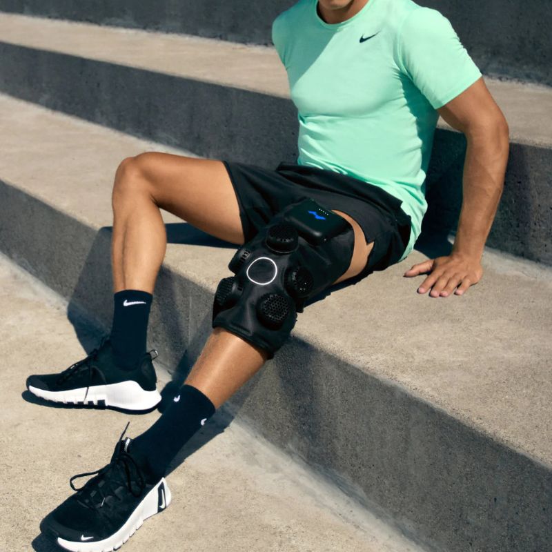 Hyperice X 2 Knee - Worn by a man sitting outdoor on concrete steps