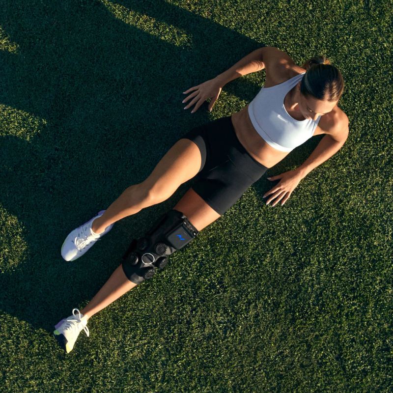Hyperice X 2 Knee - worn by a woman laying in an open field