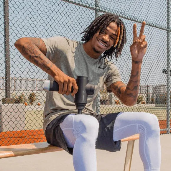 Hypervolt 2 Pro Massage Gun - A man sitting on a bench while using massage gun on his leg