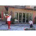 Powernet 16x10 FT Sports Barrier Net 1153 -  A man stands in front of a batting cage, holding a baseball bat, ready to practice his swing.