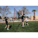 Three people using Powernet Volleyball Four Square Net in a field to play volleyball