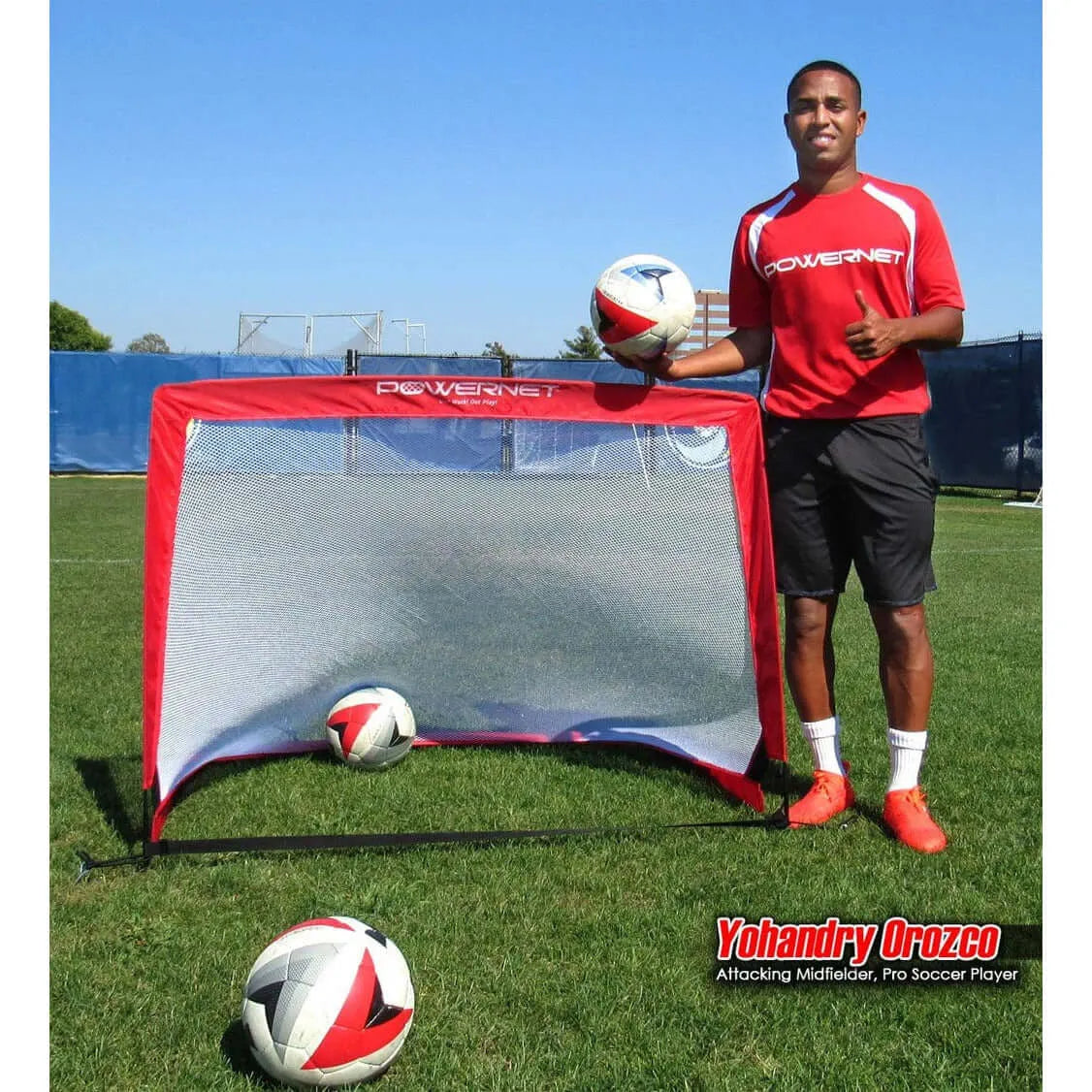 Powernet Soccer Popup Net Portable Goal 4'x3' (PAIR) S004 - Yohandry Orozco in a red shirt stands next to a small goal on a grassy field, holding a soccer ball with two balls on the ground.