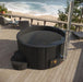 SaunaLife Model S4B Wood-Fired Hot Tub - a hot tub on a deck overlooking a beach