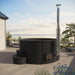 SaunaLife Model S4B Wood-Fired Hot Tub - a hot tub on a deck with the sea view in the background