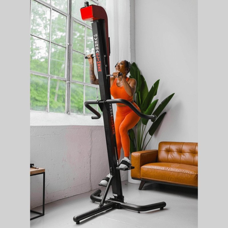 VersaClimber TSA Commercial Vertical Climber - a woman in orange workout clothes working out in a room with a big window