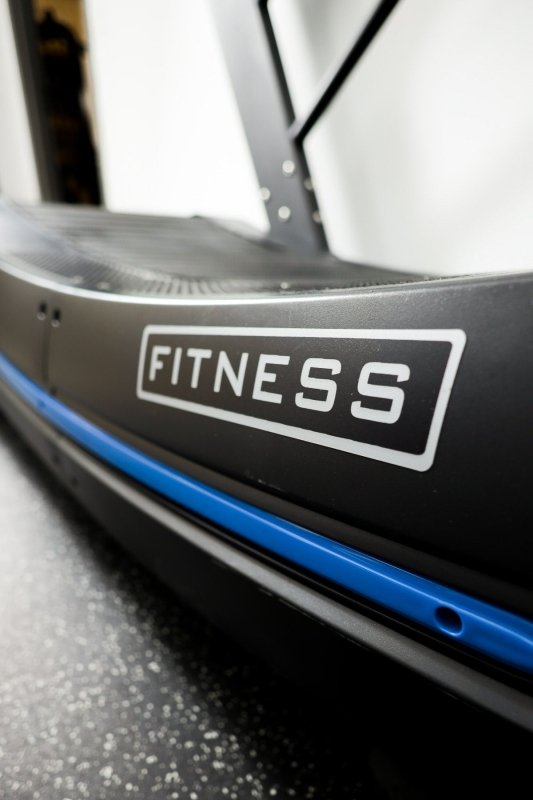 Vortex Strength CVX2500 Curved Treadmill - Close picture of the word "fitness" located at side of the running belt