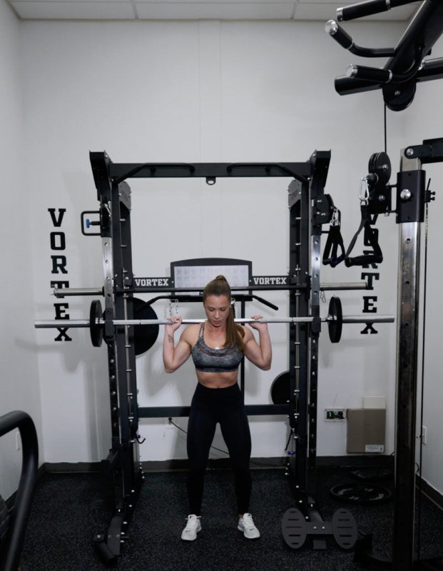 Vortex Strength VX1000 Smith Machine and Functional Trainer - Front view of the actual equipment photo with woman working out holding  a barbell