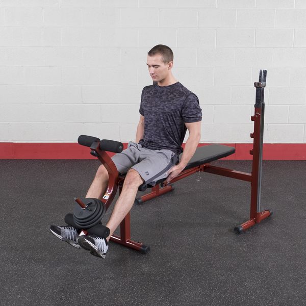 Best Fitness BFOB10 Olympic Bench With Leg Developer - man sitting on bench with weights on foot support cushioned