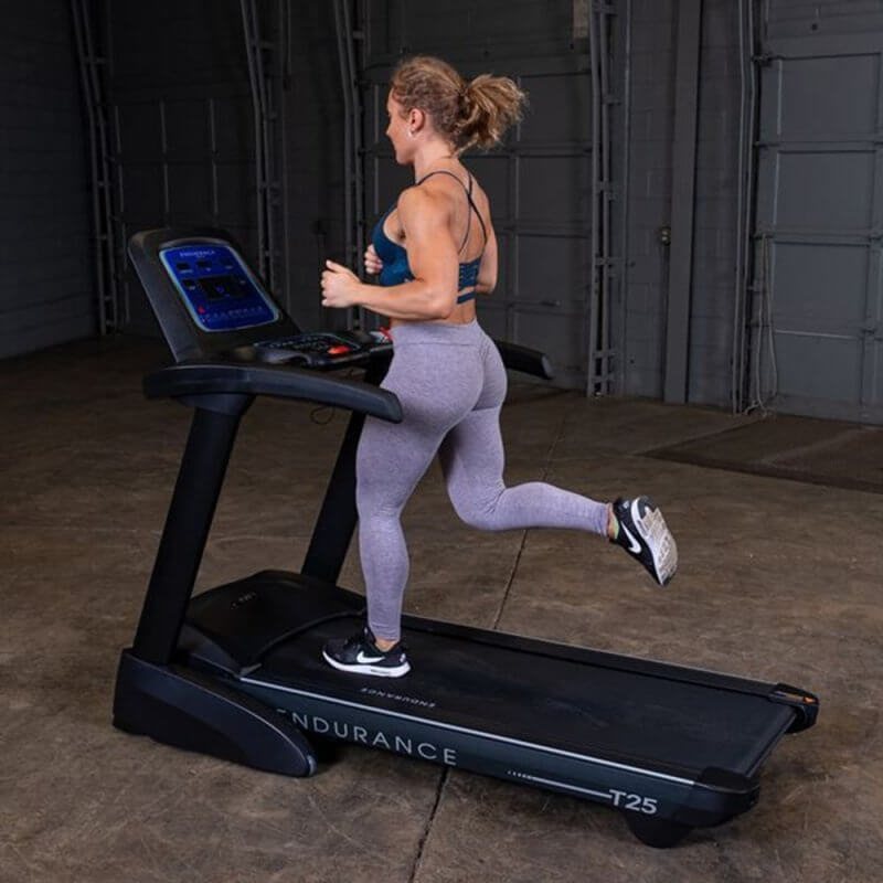 Body-Solid Endurance Folding Treadmill T25 - side view of woman running in the equipment