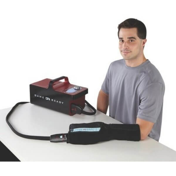 Game Ready Hand/Wrist Wrap - a man sitting at a table with handwrist wrap connected to ice machine