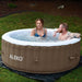 Round Inflatable Jetted Hot Tub with Cover - man and woman inside the hot tub. 